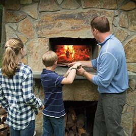 Nathan Sowers, owner of River Pizza Company, splits his time between work and being a stay-at-home Dad.  Pictured here, Nathan and his children, Ainsley and Adam, put their freshly made gourmet pizzas in their custom-built, outdoor wood-buring oven.
